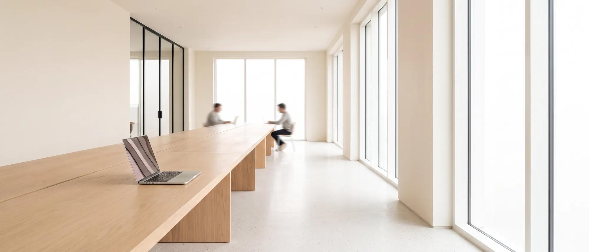 Espacio de coworking con un portátil abierto sobre una mesa de madera clara